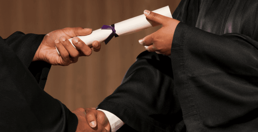 A closeup of a person receiving a diploma at a graduating ceremony